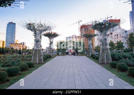 Maltepe, Istanbul, Turkey - 07.22.2021: tree road of Cumhuriyet (Republic) public park and people walking skateboarding sitting around in the evening Stock Photo