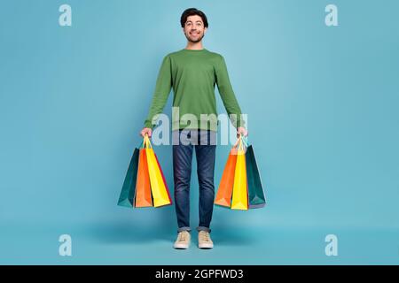 Full body photo of good looking smiling male hold shopping bags shopaholic black friday isolated on blue color background Stock Photo