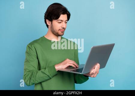 Photo of smiling focused concentrated young businessman working in computer isolated on blue color background Stock Photo