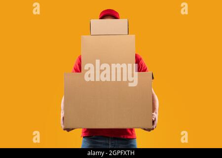 Unrecognizable Courier Holding Many Cardboard Boxes Delivering Packages, Yellow Background Stock Photo