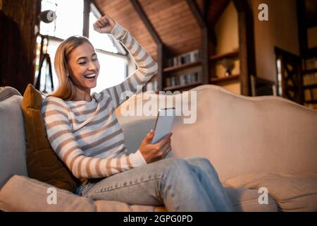Excited woman using phone shaking clenched fist Stock Photo