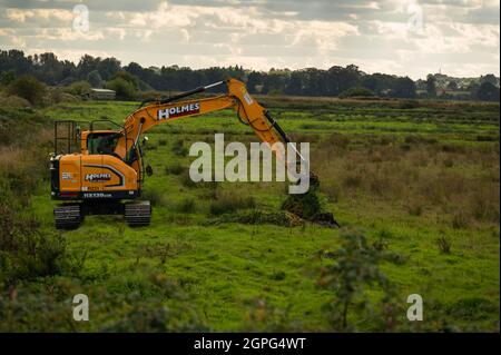 A  digger maintaining drainage ditches on low-lying grazing marsh on the Norfolk Broads at Buckenham Marshes Stock Photo