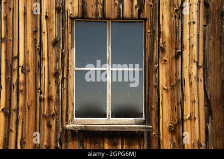 Old weathered wooden exterior barn window with vertical plank siding Stock Photo