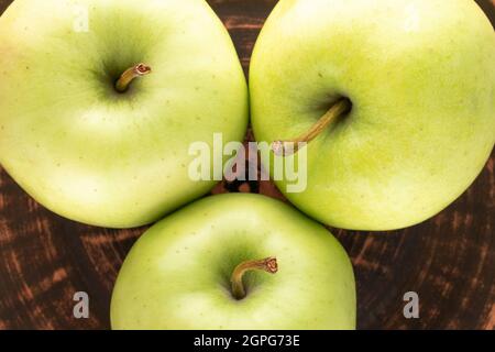Three ripe sweet apples on a clay dish, close-up, top view. Stock Photo