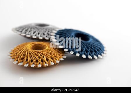gray, blue and yellow sewing thread on round bobbins isolated on white background Stock Photo
