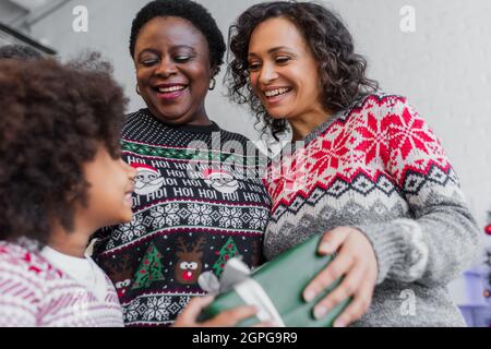 low angle view of happy african american women giving christmas present to blurred girl Stock Photo
