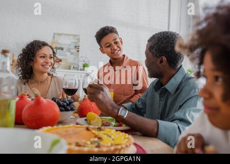 smiling african american boy talking to grandfather during thanksgiving dinner with family Stock Photo