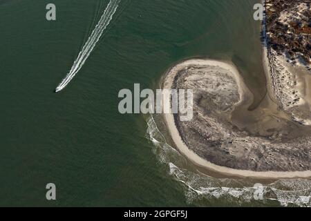A boat passes a sand swirl on the southwest end of Folly Beach, South Carolina known locally as the Edge of America. Stock Photo