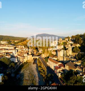 France, Vaucluse, Vaison la Romaine, Roman bridge over Ouveze River dating 1st century AD between the lower town and the medieval city with the belfry tower dated 14th century, former city hall and Mount Ventoux in the background (aerial view) Stock Photo