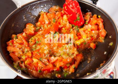 Preparation of the traditional Colombian hogao or criollo sauce (salsa criolla) made of onion, tomato, peppers and cilantro Stock Photo