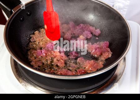 Preparation of the traditional Colombian hogao or criollo sauce (salsa criolla) made of onion, tomato, peppers and cilantro Stock Photo