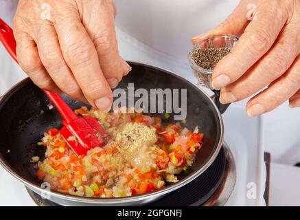 Preparation of the traditional Colombian hogao or criollo sauce (salsa criolla) made of onion, tomato, peppers and cilantro Stock Photo