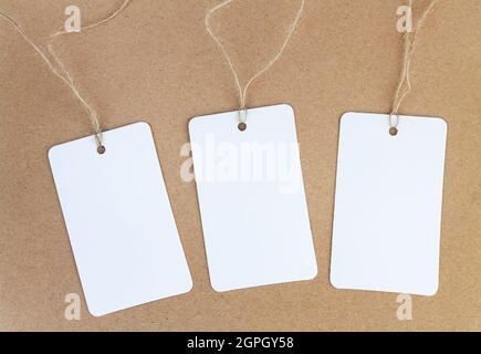 Set of three blank white paper cloth labels or price tags on brown background Stock Photo