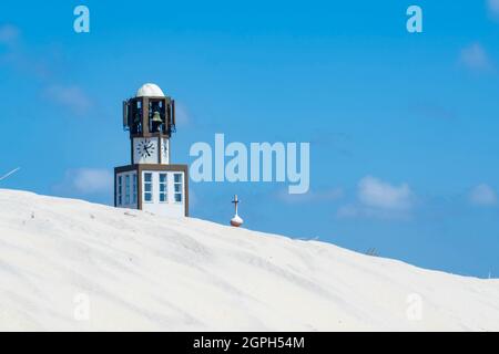 View of the Aveiro church clock between the white sand dunes of the beach on a blue sky summer day. Stock Photo