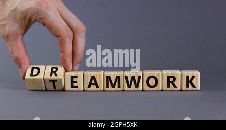 Teamwork and dream work symbol. Businessman turns wooden cubes and changes the word 'dreamwork' to 'teamwork'. Beautiful grey background. Business, te Stock Photo