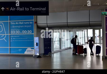 Inside Birmingham International Train Station passengers in silhouette with bags going to 'Air-Rail Link' system Stock Photo