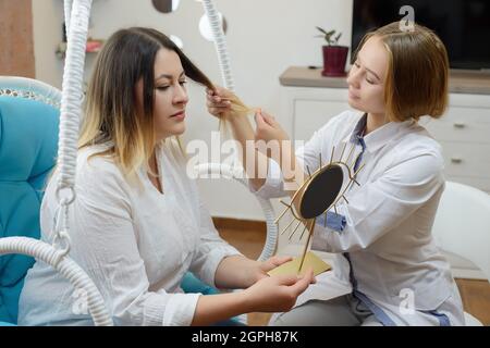 Woman visits young cosmetologist doctor. The doctor consults with the patient Stock Photo