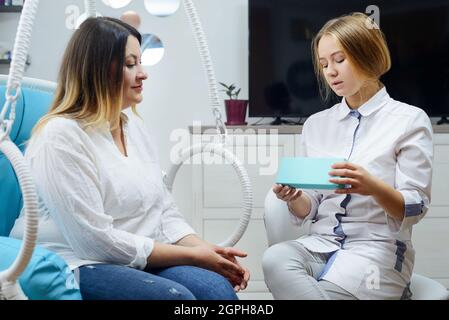 Woman visits young cosmetologist doctor. The doctor consults with the patient Stock Photo