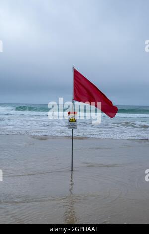 A Red Lifeguards Warning Flag (With Warning Sign) On A Cornish Beach Stock Photo