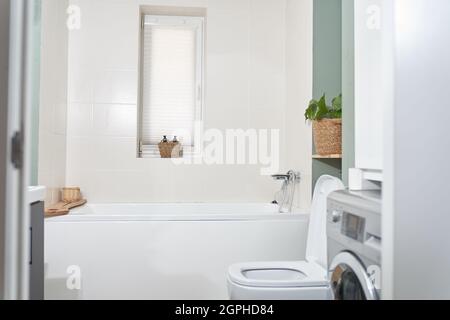 Beautiful bathroom in a new luxury house. The room has an elegant bathroom, a washing machine and a window. High quality photo Stock Photo