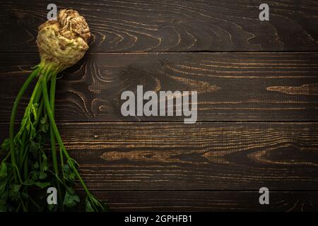 Root vegetable celera with green leaves on a wooden background, farm vegetables Stock Photo