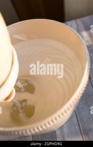 Step by step the process of making sour cream. Sour cream and sugar are whipped in a mixer bowl with whisk. Stock Photo