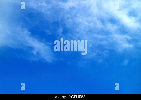 White feathery clouds spread on vibrant blue sky Stock Photo