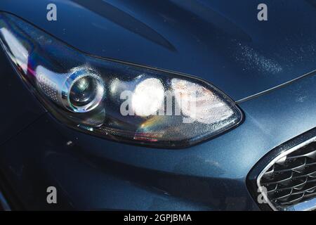 Hood of modern car after rain with drops on a headlight and body. Stock Photo