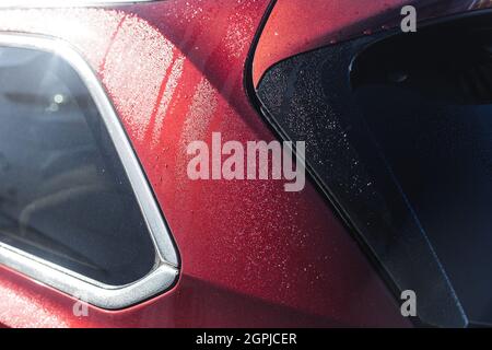 Shining red metallic car with raindrops, closeup photo with selective focus Stock Photo