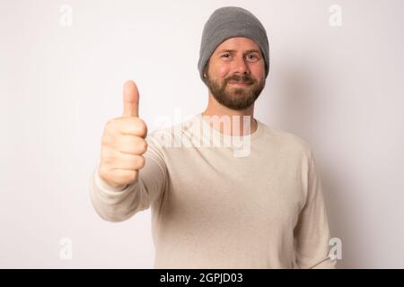 Young handsome caucasian man wearing casual clothes and wool cap smiling happy. Stock Photo
