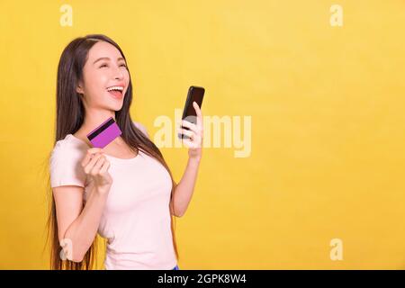 Happy young  woman  using phone and holding credit card. Stock Photo