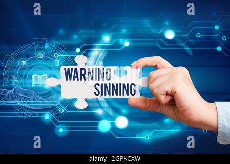 Text showing inspiration Warning Sinning. Business concept stop the action which is believed to break the laws Hand Holding Jigsaw Puzzle Piece Stock Photo