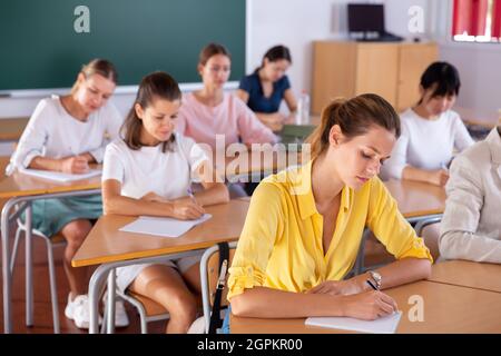 Students writing in notepads during lesson Stock Photo