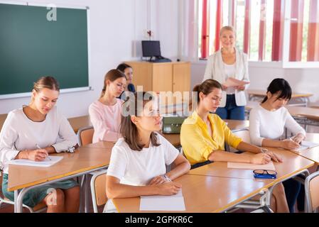Students writing in notepads during lesson Stock Photo