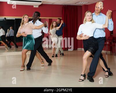 Adult couples dancing salsa dance together in modern studio Stock Photo