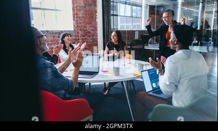 businesswoman of the month. Cheerful young businesswoman smiling while being applauded by her colleagues in a modern office. Happy young businesswoman Stock Photo