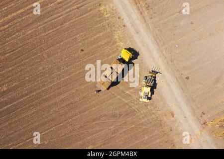 Tractor loading Hay Bales onto a parked Truck, Aerial view. Stock Photo
