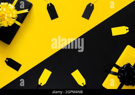 Yellow and Black gift boxes with ribbon and blank price tags put on black and yellow background. Black friday and Boxing day concept. Stock Photo