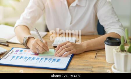 Cropped shot of Senior female manager reviewing her assistant's work and making notes on sticky note for more ideas Stock Photo