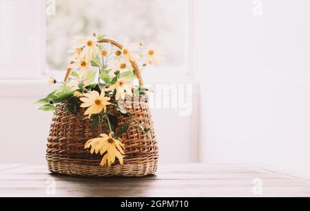 Yellow garden autumn flowers in a basket on a white table. Vintage still life. Front view copy space Stock Photo