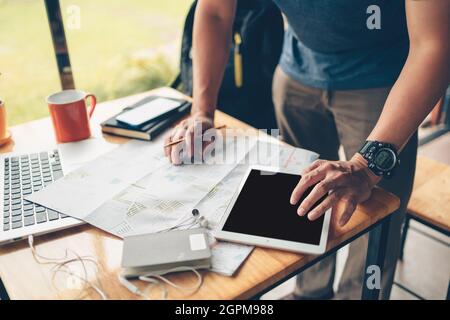 Tourist planning vacation use tablet for search and check hotel and travel accessories around on the table. Vocation, travel, holidays and backpack co Stock Photo