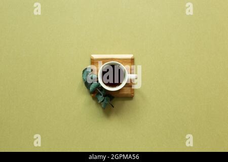 Cup of coffee with eucalyptus leaf on khaki background. top view, copy space Stock Photo