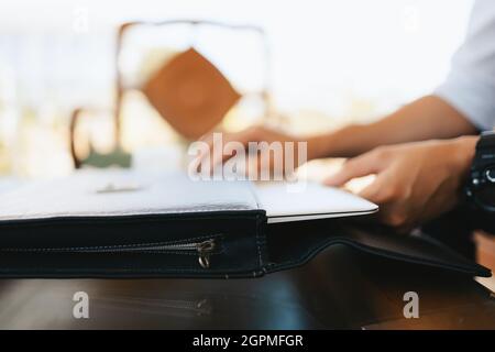hand pulling laptop out of laptop bag on the table. Stock Photo