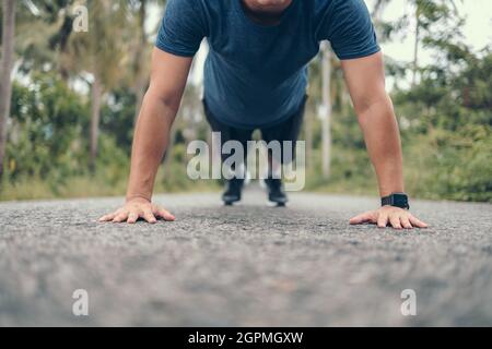 Young sportsman doing push-ups in the park. Fitness, training, workout concept. Stock Photo