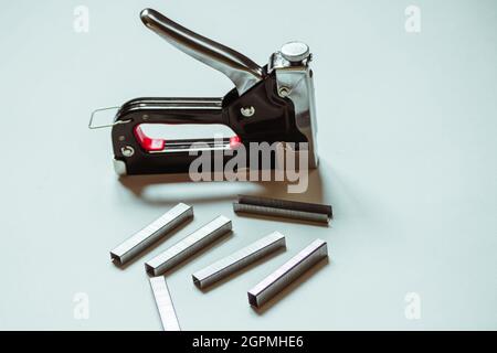 Furniture construction stapler next to staples on a white background.  Stock Photo
