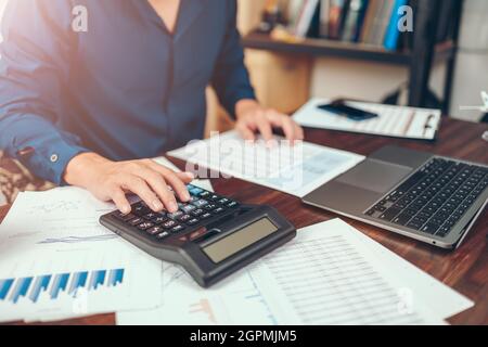 accountant working and analyzing financial reports and use calculator on office desk. finance and business concept. Stock Photo
