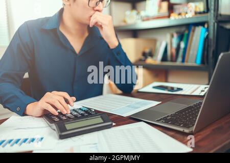 accountant working and analyzing financial reports and use calculator on office desk. finance and business concept. Stock Photo
