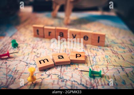 Wood square with word "map" and "travel" on the map. pushpin showing the location of a destination point on a map. Travel plan concept. Stock Photo
