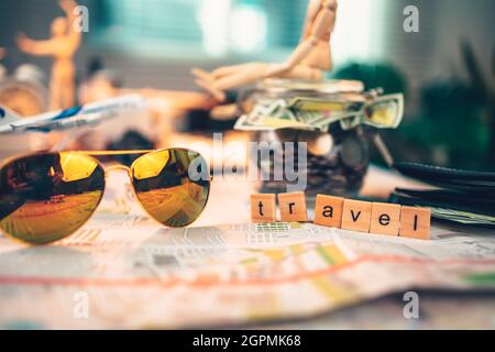 Wood square with word "travel", sun glasses and  money in jar on the map. travel plan concept. Stock Photo