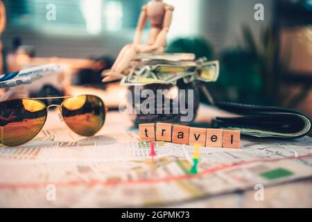 Wood square with word "travel", sun glasses and  money in jar on the map. travel plan concept. Stock Photo